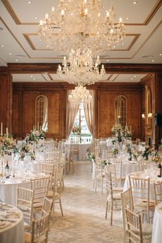 a room filled with lots of tables covered in white clothed tablecloths and tall chandeliers