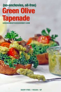 green olive tapenade with tomatoes and mushrooms on toasted bread next to a jar of pesto sauce