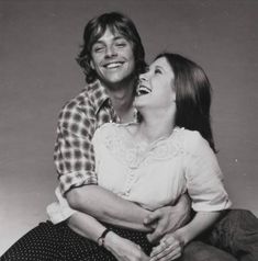 a man and woman sitting next to each other on the floor smiling at one another