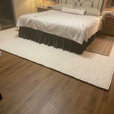 a large bed sitting on top of a hard wood floor next to a night stand