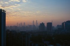 the sun is setting over a city with tall buildings and skyscrapers in the background