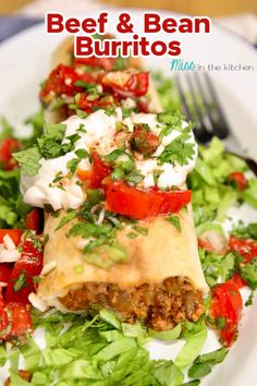 beef and bean burritos on a plate with lettuce, tomatoes and feta cheese