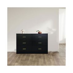 an empty room with a black dresser and two lamps on top of it, in front of a white wall