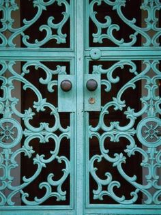 an ornate iron door with two knobs on the front and side panels that have been painted aqua blue