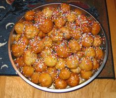 a bowl filled with lots of food on top of a wooden table next to a rug