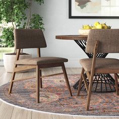 a dining room table with two chairs and a bowl of fruit on top of it