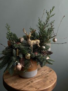 a potted plant with ornaments on top of a wooden table next to a gray wall