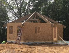 a house is being built in the middle of some trees and dirt with a ladder on it