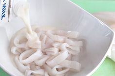 a bowl filled with noodles and milk being poured into it