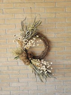 a dried wreath on a brick wall with flowers in the middle and leaves around it