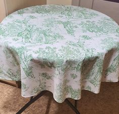 a green and white table cloth on top of a round table