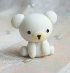 a small white teddy bear sitting on top of a bed