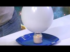 a white balloon sitting on top of a blue plate with a candle in the middle