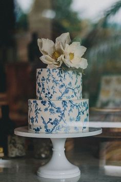 there is a blue and white cake with flowers on the top it sits on a table