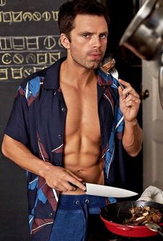 a shirtless man holding a knife and fork in front of a pan with food on it