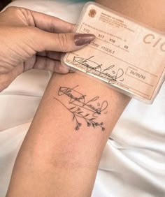 a woman's arm with a tattoo on it and a check card in her other hand