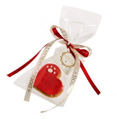 a heart shaped cookie in a cellophane bag with a red ribbon on it