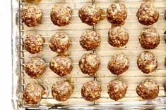 a baking tray filled with meatballs on top of a metal cooling rack next to an orange peel