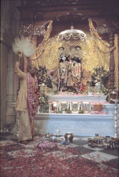 a man standing in front of a shrine with flowers on the ground and petals all around him