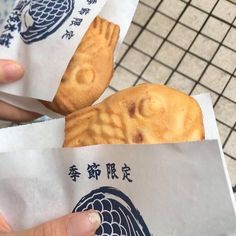 a person holding two pieces of food in their hands with chinese writing on the paper