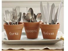 four pots with forks and spoons in them sitting on a plate next to silverware