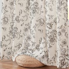 a curtain with floral print on it in front of a wooden floor and window sill