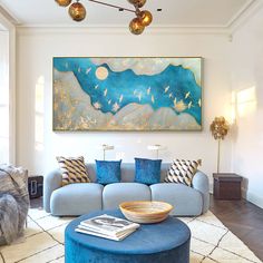 a living room filled with furniture and a large painting on the wall above it's couch