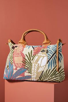 a handbag with an exotic print on it, sitting on a pink surface in front of a pink wall