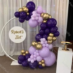 purple and gold balloons are arranged in the shape of a letter on top of a table