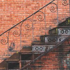 an old set of stairs next to a brick wall with wrought iron handrails