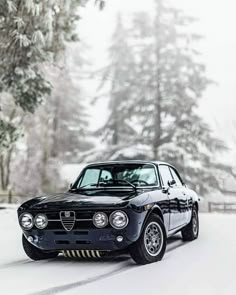 a black alfa coupe driving down a snow covered road