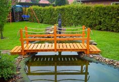 a wooden bridge over a small pond in a garden