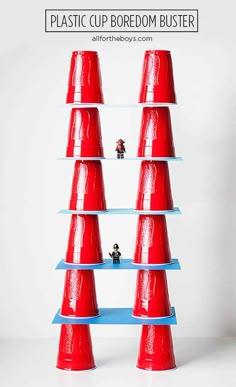 several red cones stacked on top of each other in front of a white wall with small toy figures