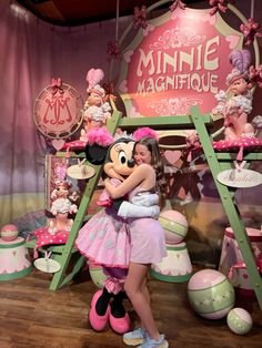 a girl hugging minnie mouse in front of a display