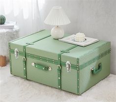 a green suitcase sitting on top of a white rug next to a lamp and table