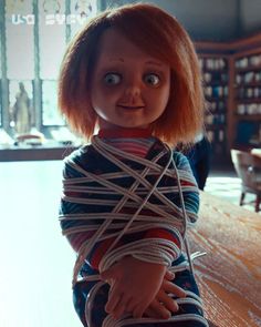 a creepy doll tied up to a table