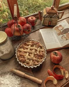 an apple pie sitting on top of a wooden table next to apples and other fruit