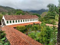 an aerial view of a house surrounded by greenery and trees with mountains in the background