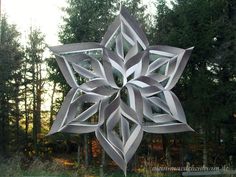 a large metal snowflake sitting in the middle of a forest