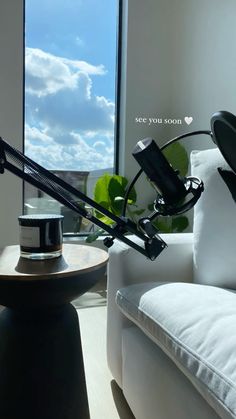 a desk lamp sitting on top of a table next to a white couch in front of a window