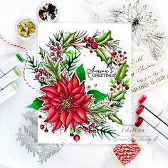 a christmas card with poinsettis and holly on it, surrounded by other holiday decorations