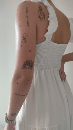 the back of a woman's dress with tattoos on her upper arm and shoulder