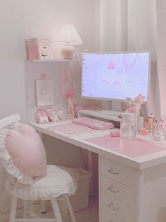 a white desk topped with a computer monitor next to a pink chair and table lamp