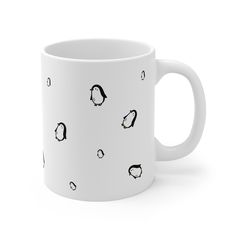 a white coffee mug with penguins all over it on a white background that has black dots in the middle