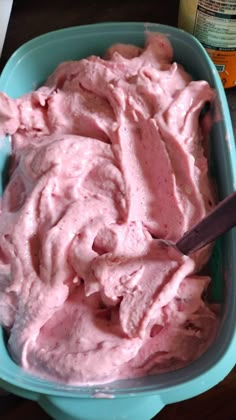 a bowl filled with pink ice cream on top of a black countertop next to a knife