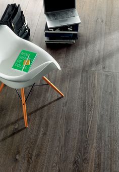 an open laptop computer sitting on top of a wooden floor next to a white chair