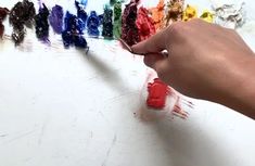 a person is painting different colors on a white surface with paintbrushes in front of them