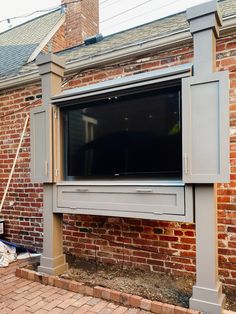 a flat screen tv mounted to the side of a brick building