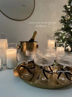 champagne glasses and candles on a tray with a christmas tree in the background that says, cutest way to elevate your drinkware