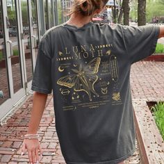 a woman is walking down the sidewalk with her hand on her hip and wearing a t - shirt that says lunaa moth